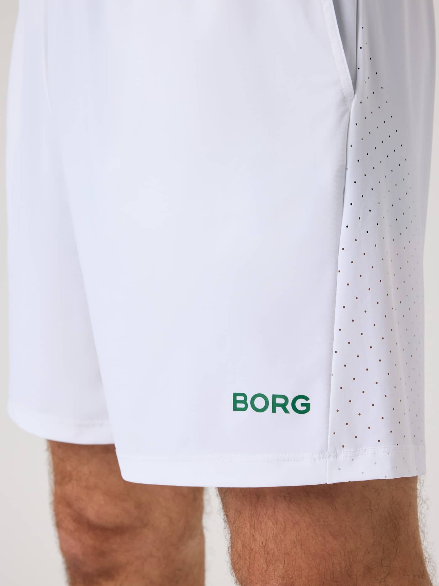 Side view of the men's Borg Golf Sports Shorts 8 Inch in Brilliant White (White) with a green logo and perforated panels. - Image 4