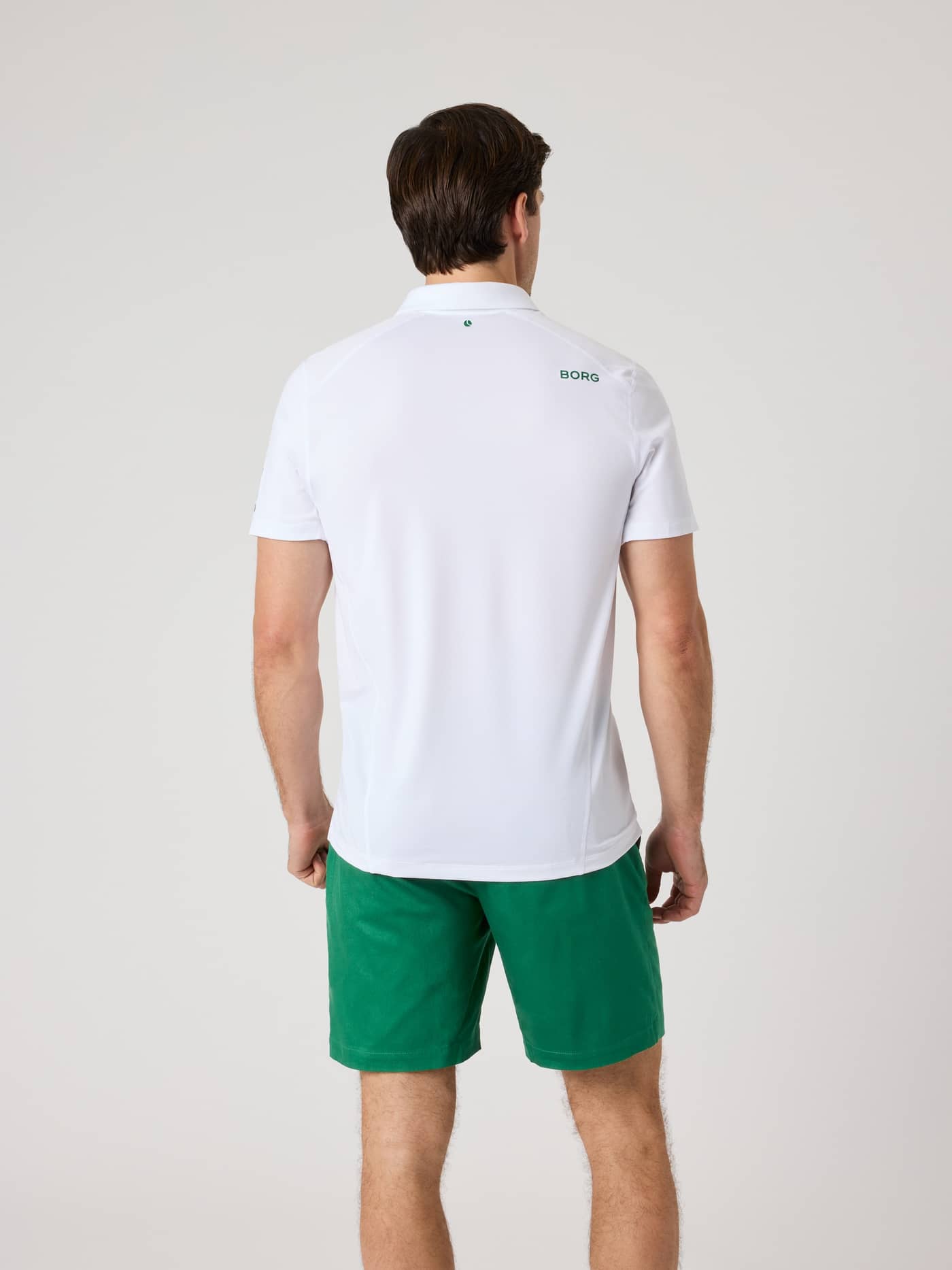 Vue de dos d'un homme portant le Borg Golf Polo Shirt en Brilliant White (Blanc) avec un logo BORG vert sur l'épaule. - Image 2