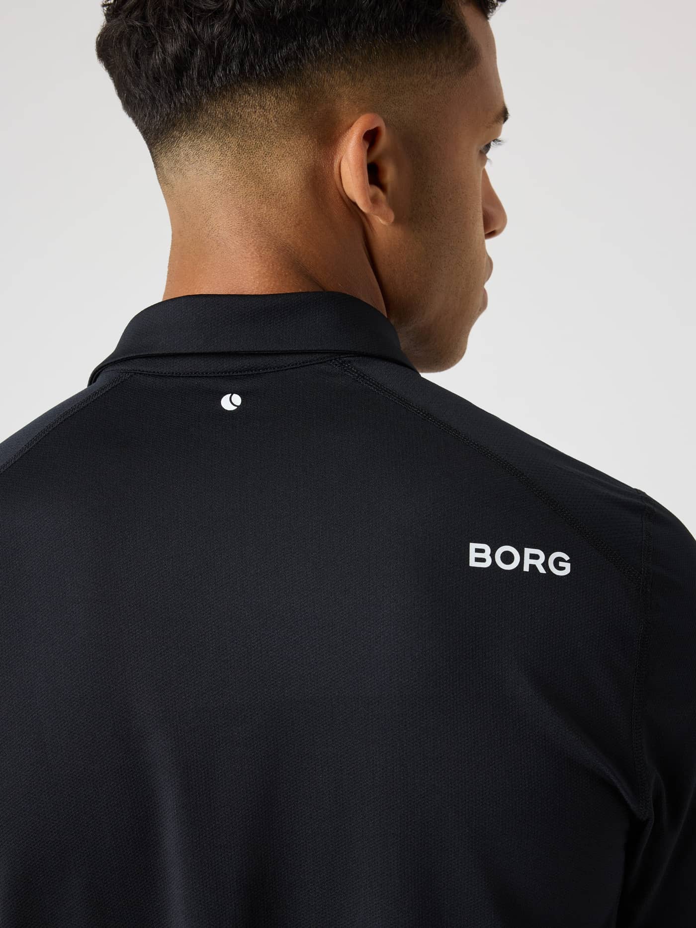 Back view of the men's Borg Golf Polo Shirt in Black Beauty (Black) with white logos and breathable mesh fabric. - Image 6