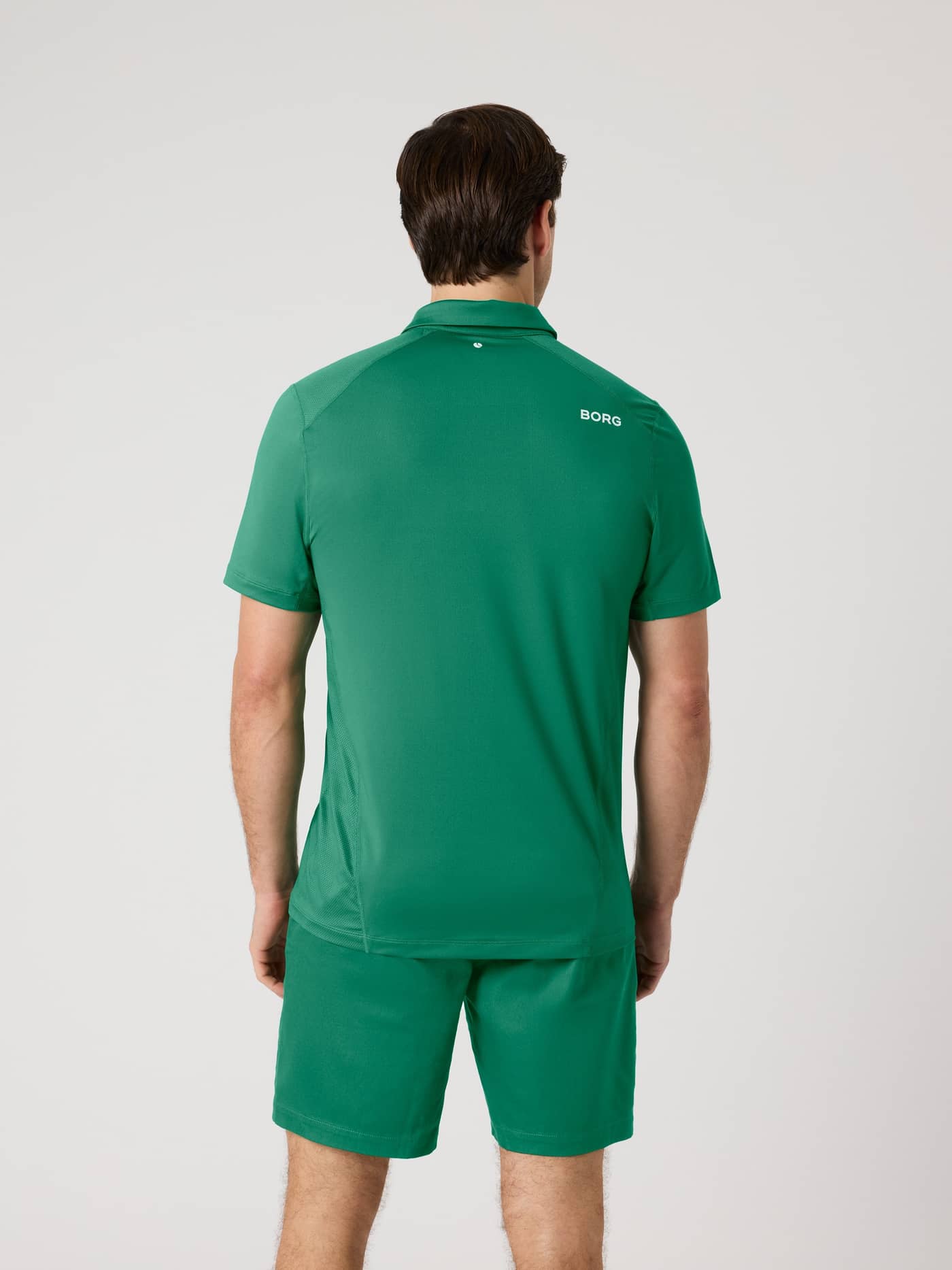 Back view of a man wearing the Björn Borg Golf Polo Shirt in Verdant Green (Green) with a white logo and tennis ball print. - Image 2