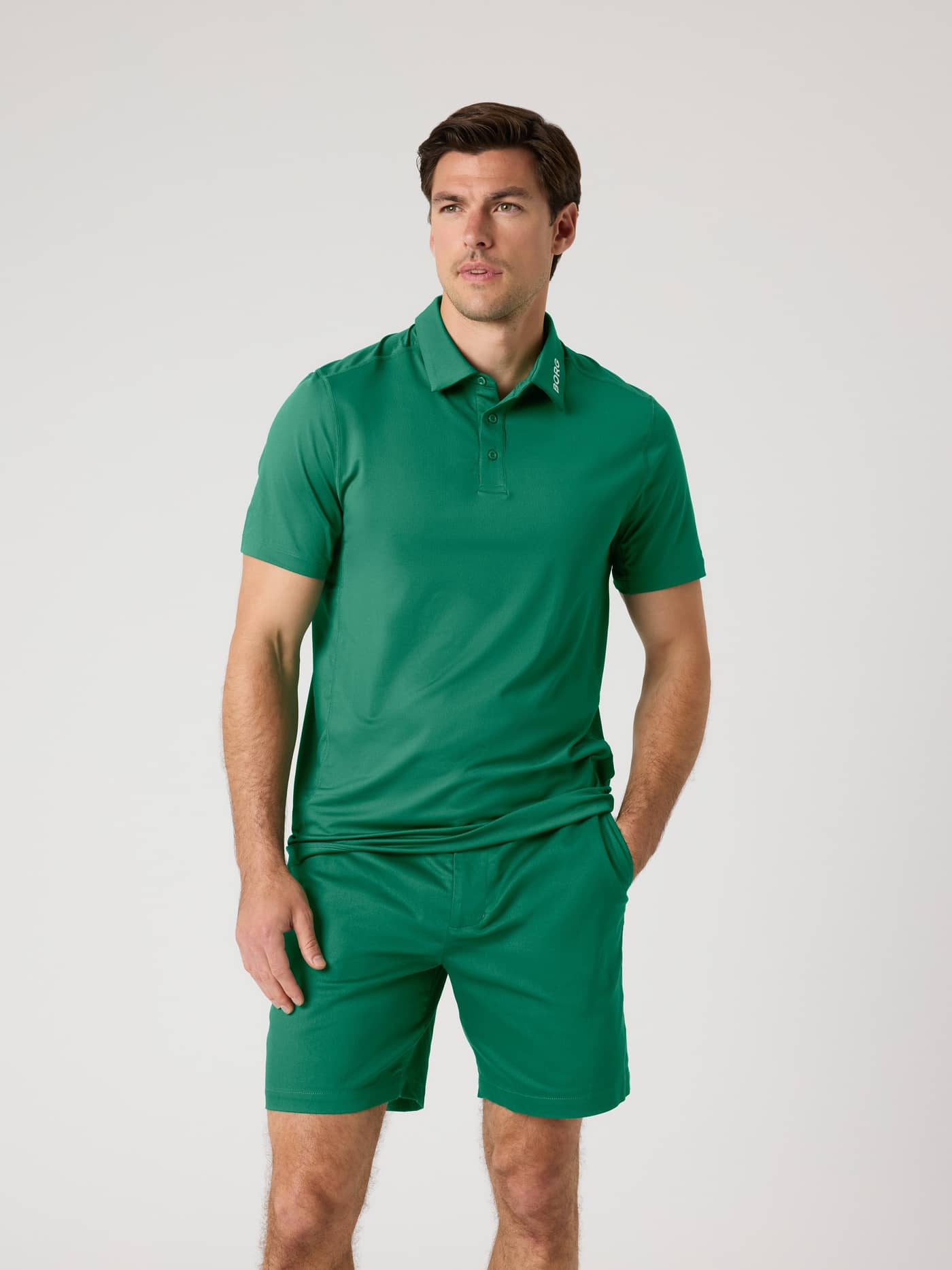 Vue de face d'un homme portant le Borg Golf Polo Shirt en Verdant Green (Vert) et un short fonctionnel pour le golf. - Image 1