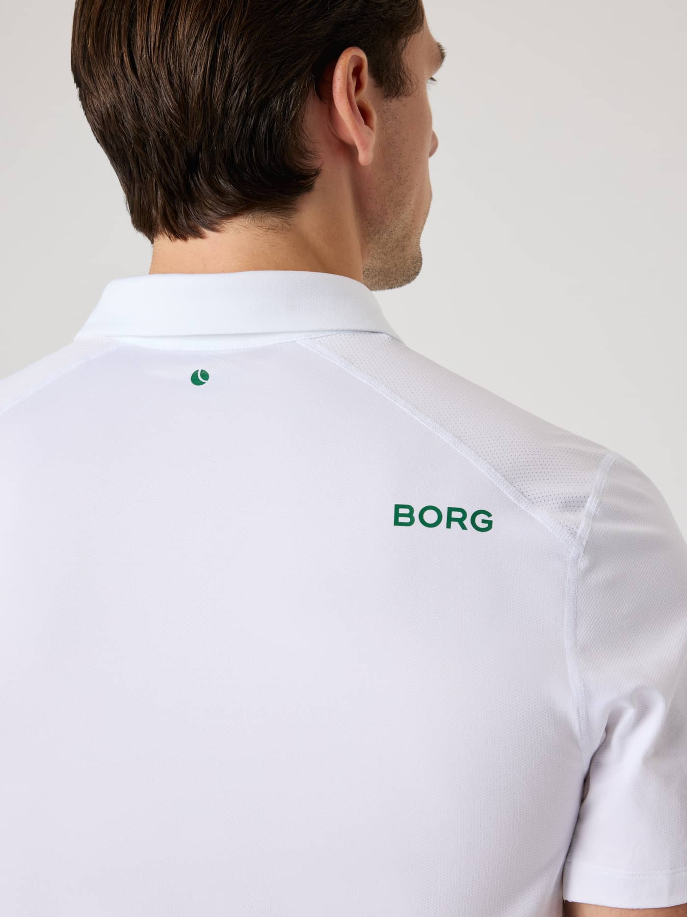 Vue de dos du Borg Golf Polo Shirt en Brilliant White (Blanc) avec logos verts et panneaux en mesh pour le golf. - Image 4