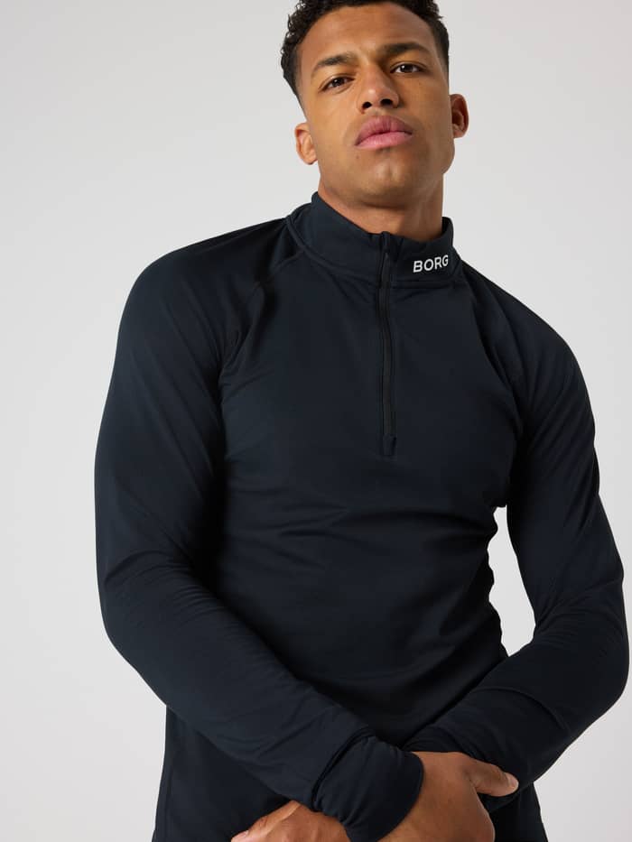 Front view of a man wearing the Borg Golf Midlayer Half Zip in Black Beauty (Black), featuring a white collar logo. - Image 5