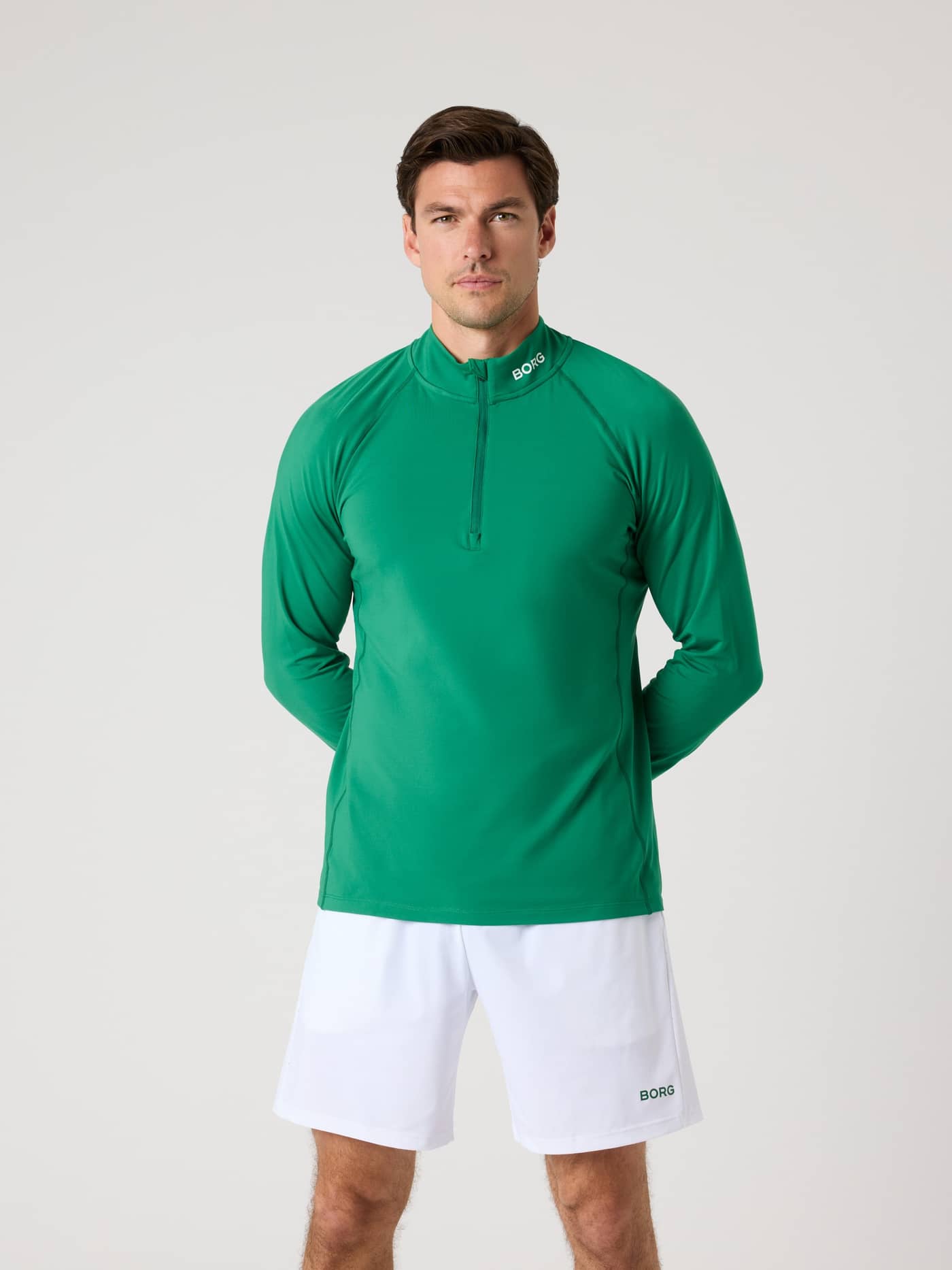 Vorderansicht eines Mannes im funktionellen Borg Golf Midlayer Half Zip in Verdant Green (Grün) mit weißem Logo am Kragen. - Image 1