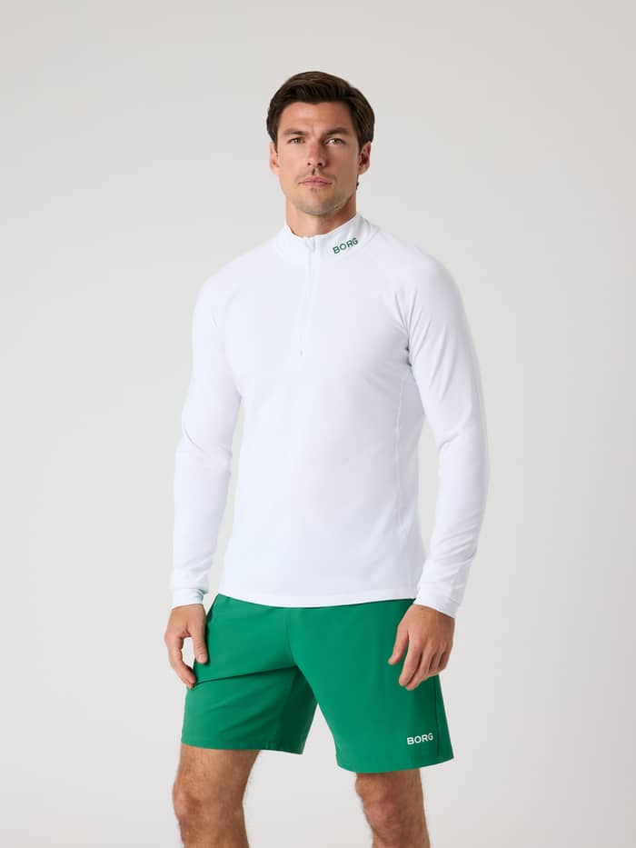 Vooraanzicht van een man in de Borg Golf Midlayer Half Zip in Brilliant White (Wit) met een groen logo voor golf.