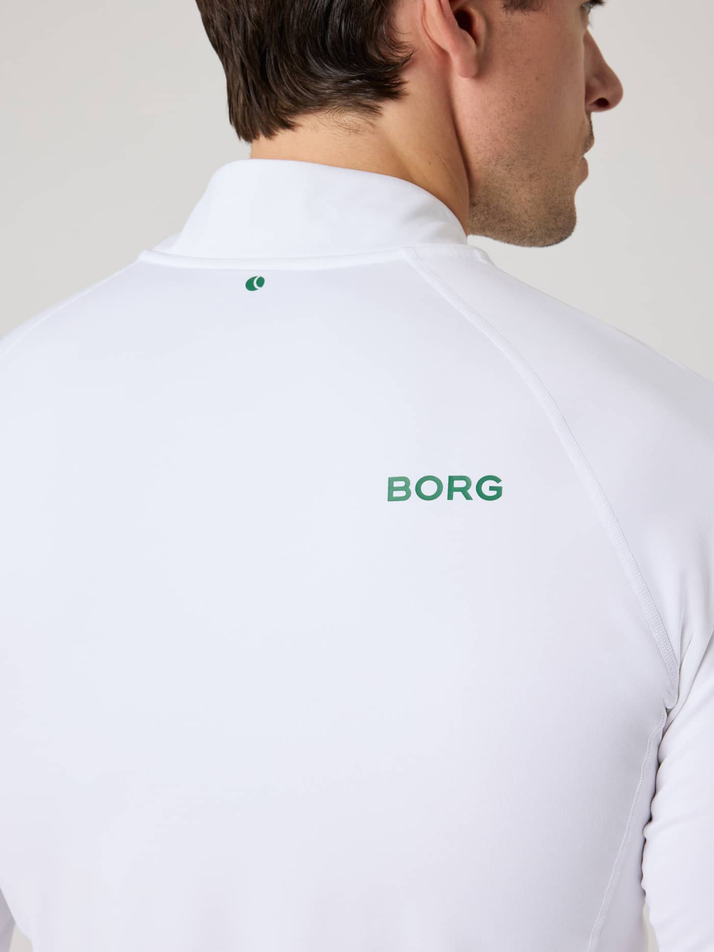 Achteraanzicht van de Borg Golf Midlayer Half Zip in Brilliant White (Wit) met groene logo's voor golf en tennis. - Image 5