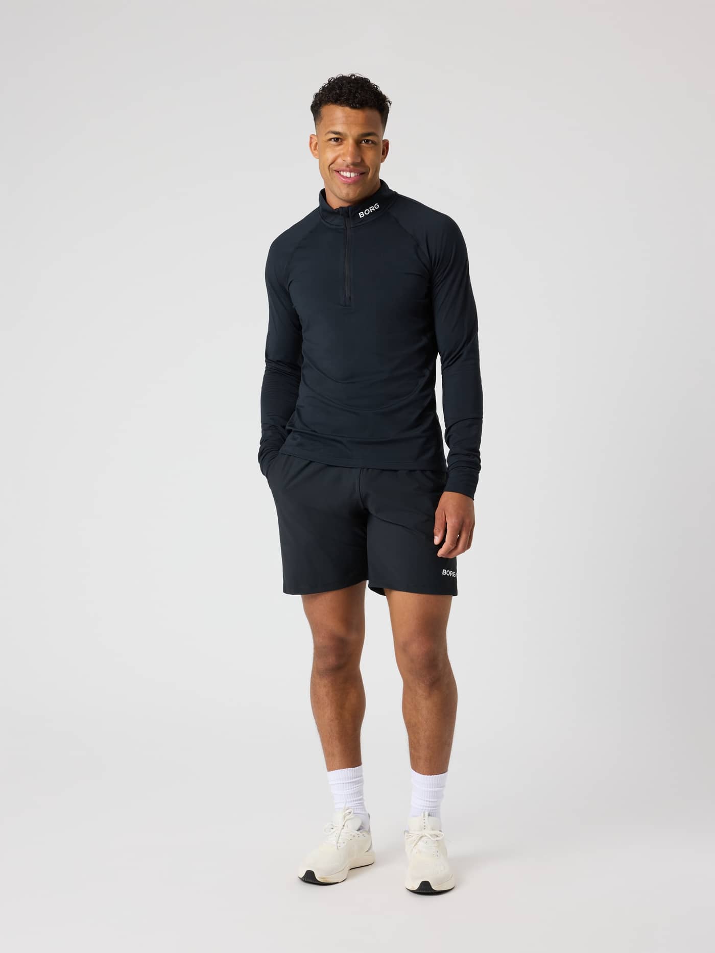 Vue de face en pied d'un homme portant le Borg Golf Midlayer Half Zip performant en Black Beauty (Noir) avec logo blanc. - Image 3