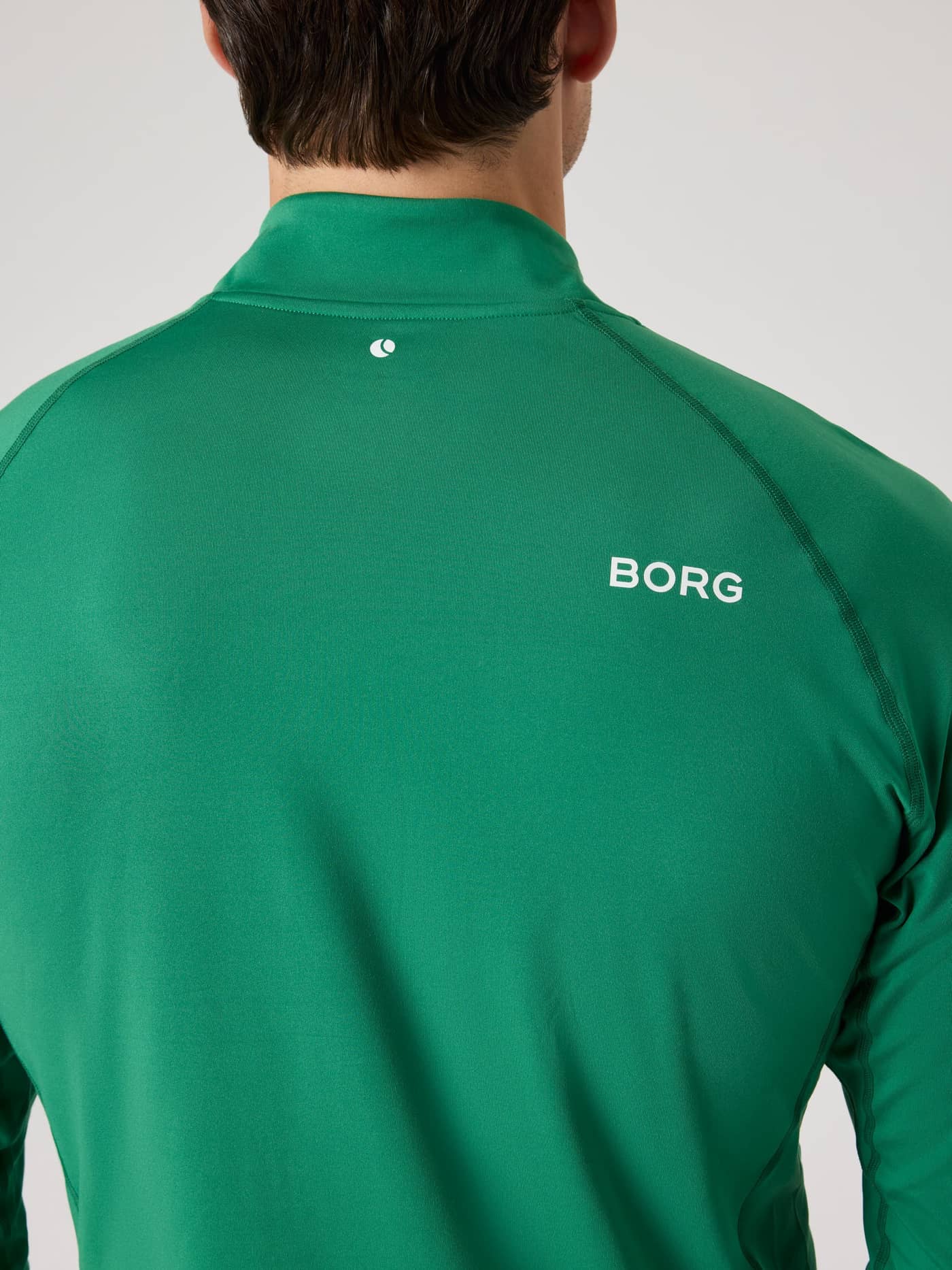Back view of a man wearing the Verdant Green (Green) Borg Golf Midlayer Half Zip, with a white logo and golf performance. - Image 5