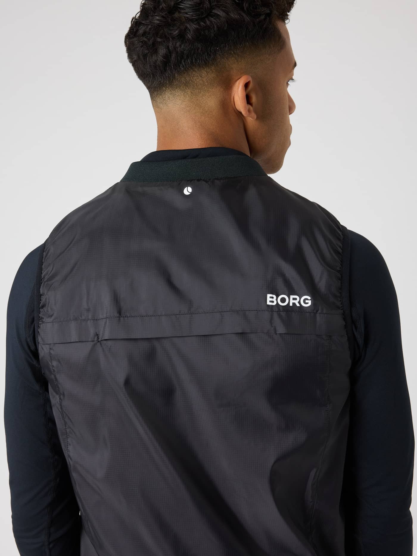 Bakside av mann i Borg Golf Vest Ripstop i Black Beauty (Svart) med hvit logo, ventilasjon i ryggen og tennisdetalj. - Image 5