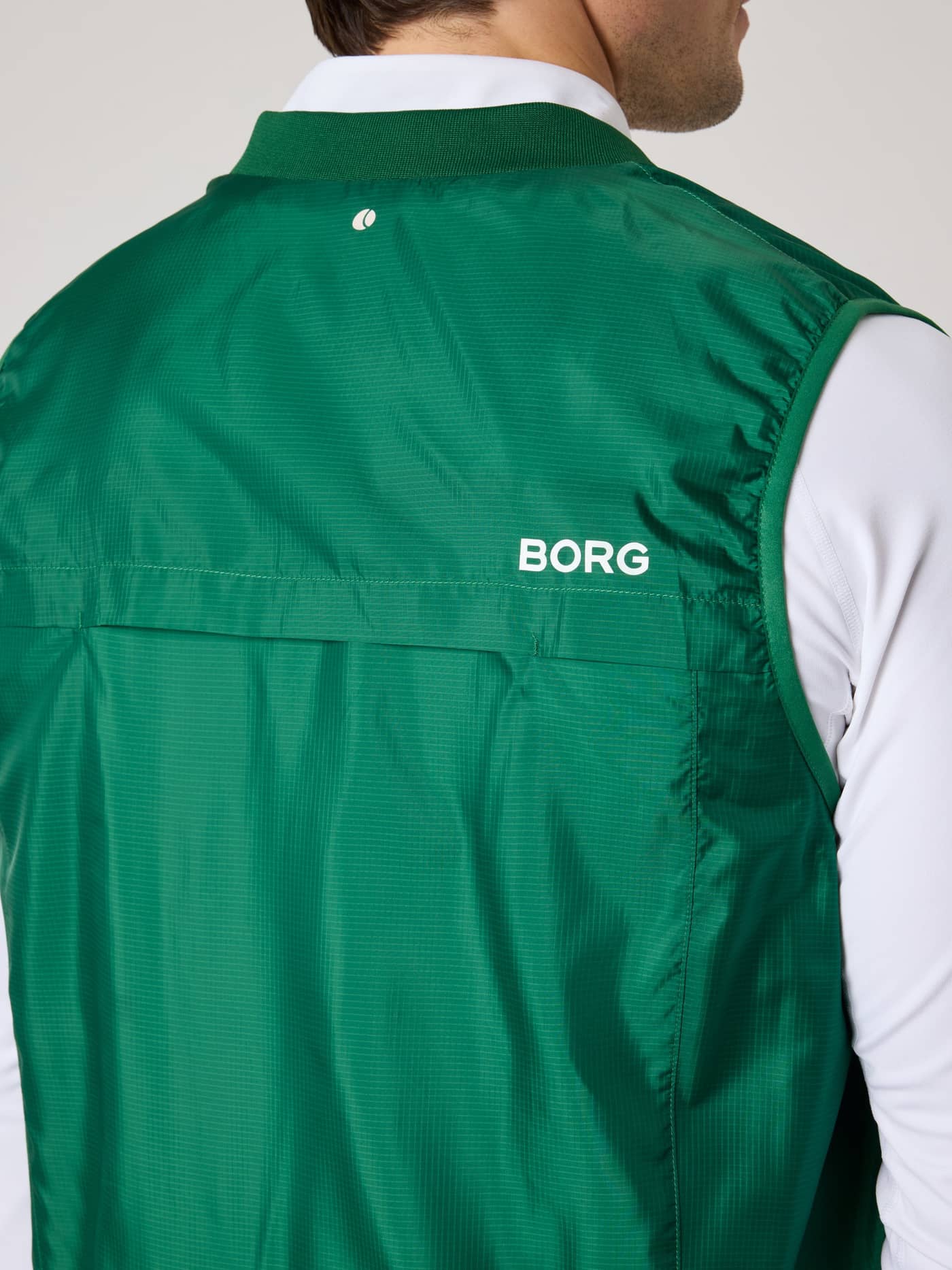 Vista posterior del Borg Golf Vest Ripstop en Verdant Green (Verde) con logo blanco y detalle de pelota de tenis para golf. - Image 4