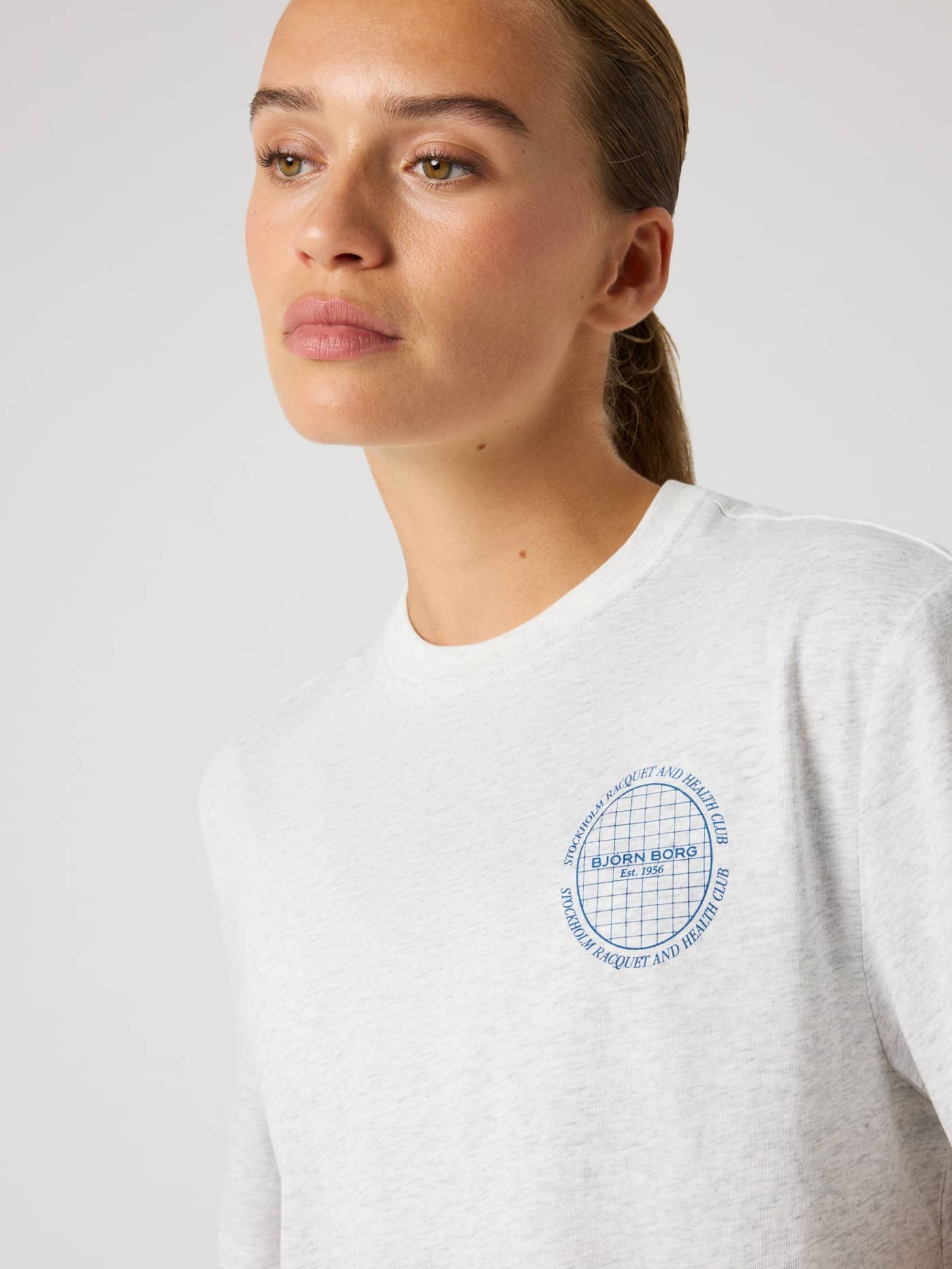 Woman wearing the cotton-blend Studio Oversized Cropped T-Shirt in Ultra Light Grey Melange (Grey) with a blue chest logo. - Image 5