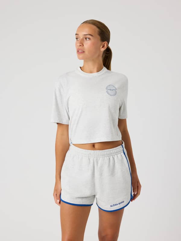 Front view of a model in the Björn Borg Studio Oversized Cropped T-Shirt in Ultra Light Grey Melange (Grey) with tennis logo.