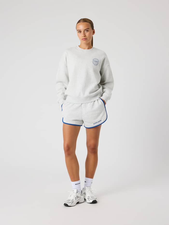 Vorderansicht eines Models im oversized Borg Boyfriend Sweatshirt in Ultra Light Grey Melange (Grau) mit Shorts für Tennis. - Image 4