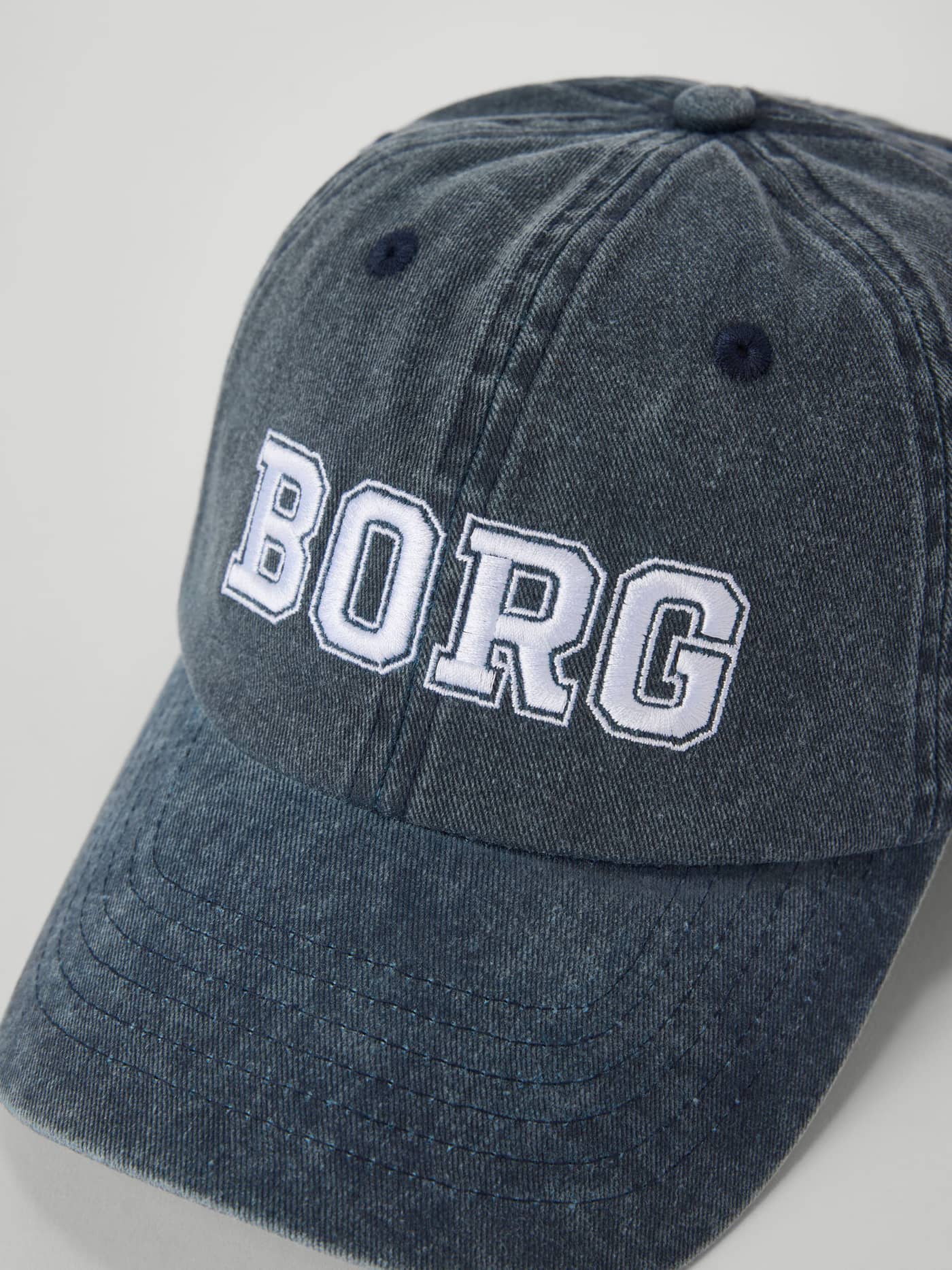 Nærbillede forfra af Borg Washed Bold Logo Cap i Night sky (Blå) med hvidt BORG-broderi på vasket økologisk bomuld. - Image 3