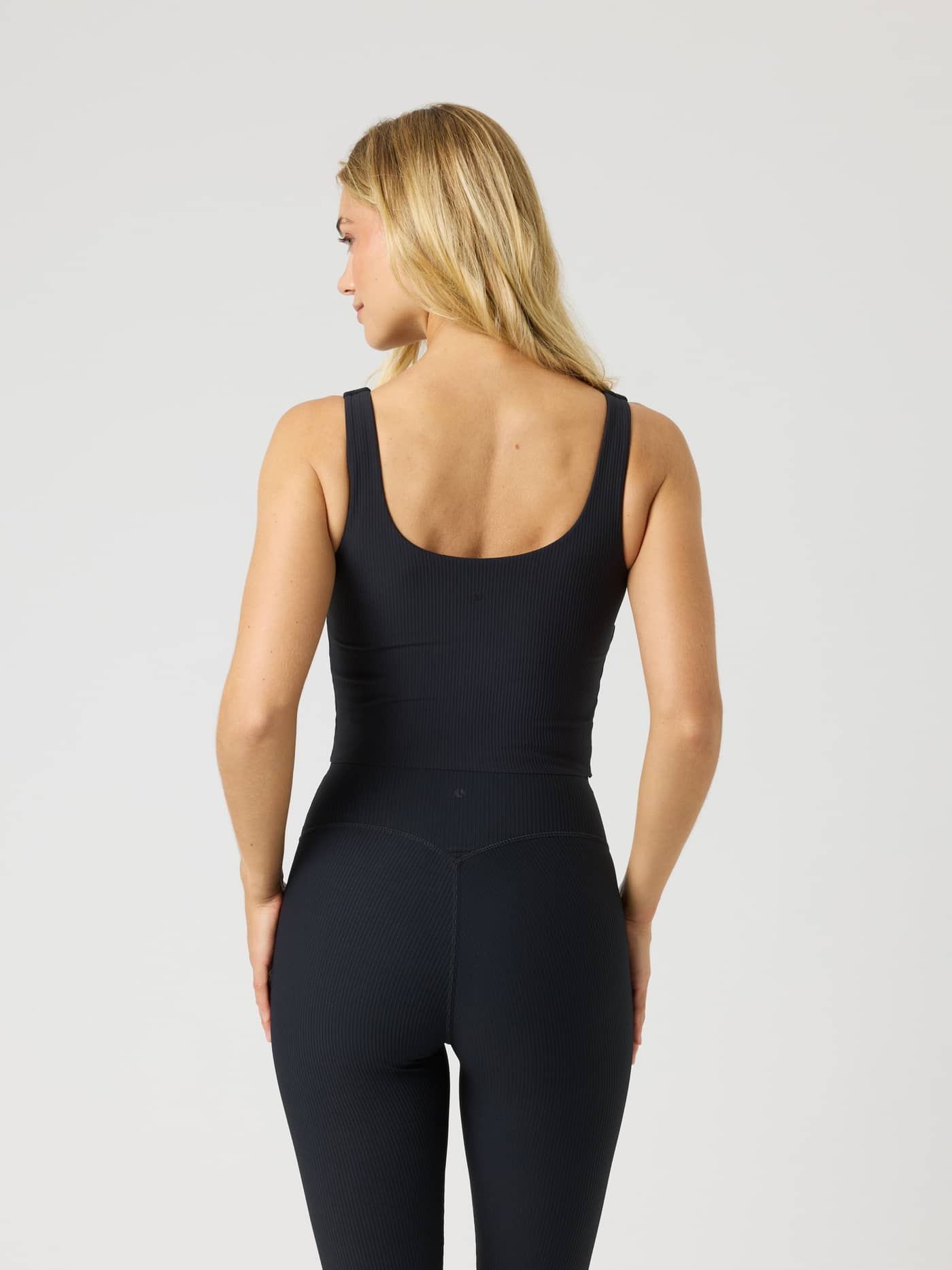 Back view of a model wearing the slim-fit Studio Ribbed V-Neck Top in Black Beauty (Black) for training. - Image 2