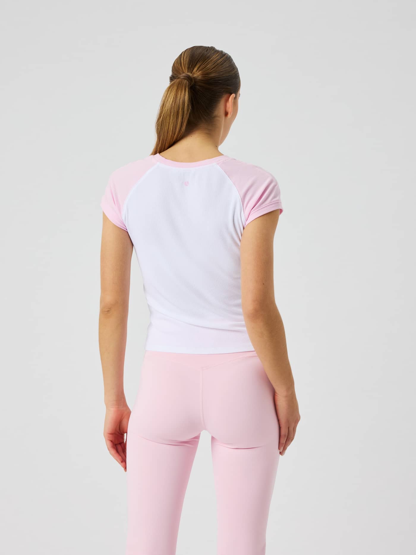 Back view of a model in the Studio Ringer T-Shirt in Pink Lady (Pink), showing the slim fit and tennis ball print. - Image 3