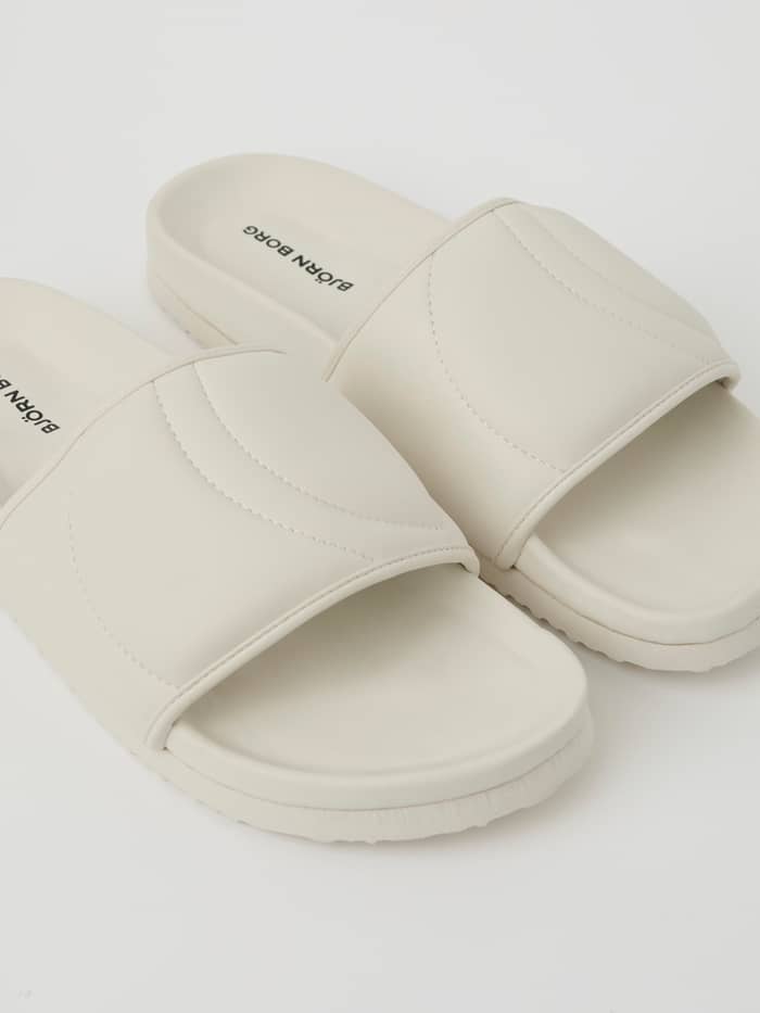 Witte Unisex Timeout Slides van duurzaam TPU met een zwart logo op het voetbed in een gedetailleerde close-up. - Image 2