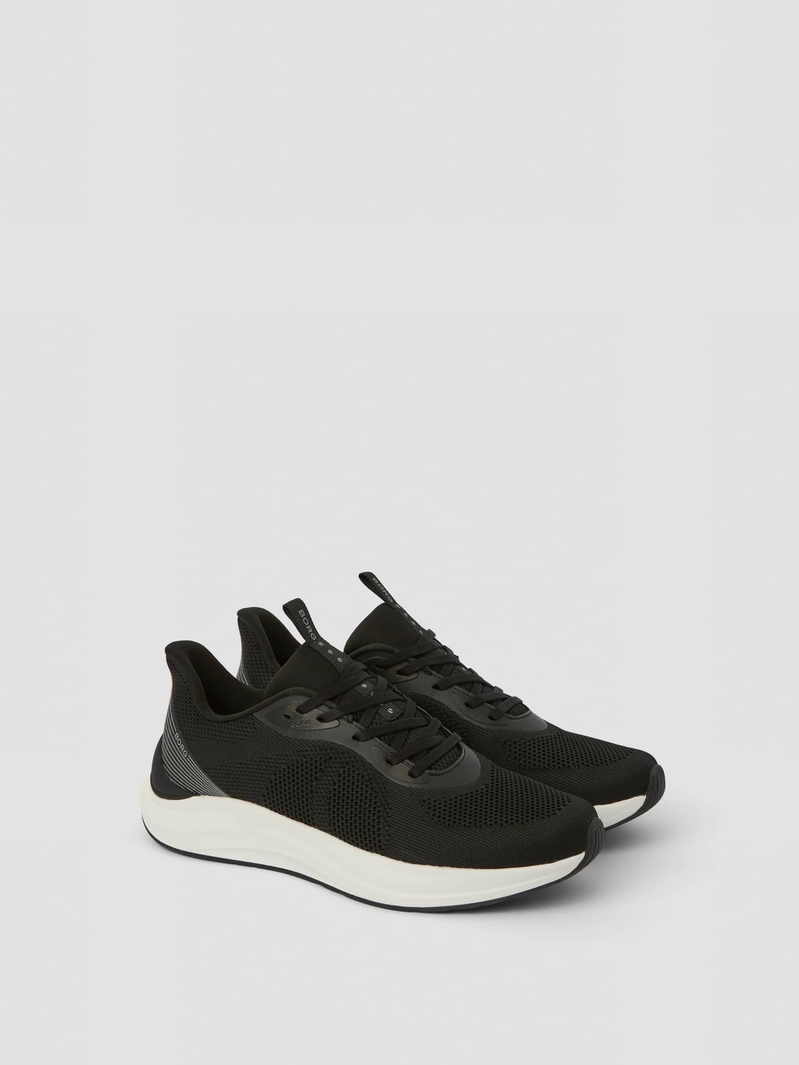 Vista de tres cuartos de las Unisex Ace Knit Sneakers en negro para running con material de punto y detalles de logo en gris. - Image 1