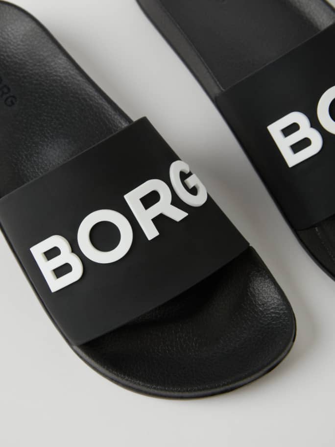 Gros plan détaillé des Unisex Knox Slides en TPU Noir durable avec un logo BORG blanc sur la bride pour un look décontracté. - Image 2