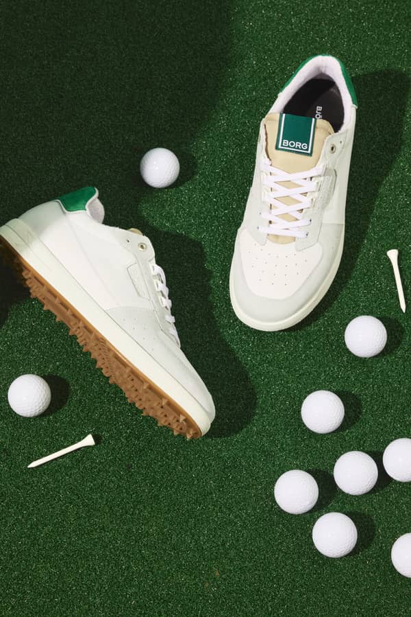 Men's Baseline Golf Sneakers en cuir blanc et vert avec logo blanc sur un terrain de golf verdoyant.