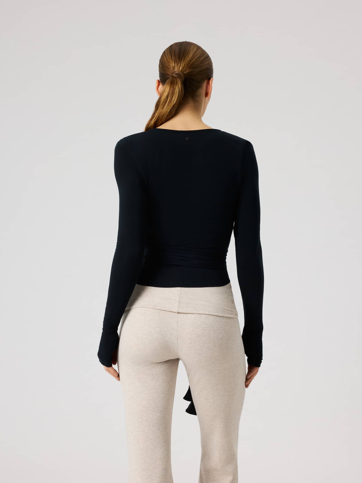 Back view of the Studio Wrapped Top in Black Beauty (Black), a slim training top with a tennis ball print at the neck. - Image 3