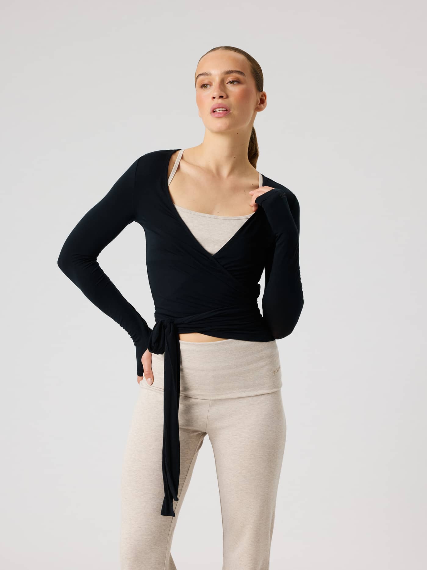 Front view of a model in the Studio Wrapped Top in Black Beauty (Black) with a slim training fit and wrap-around waist. - Image 2