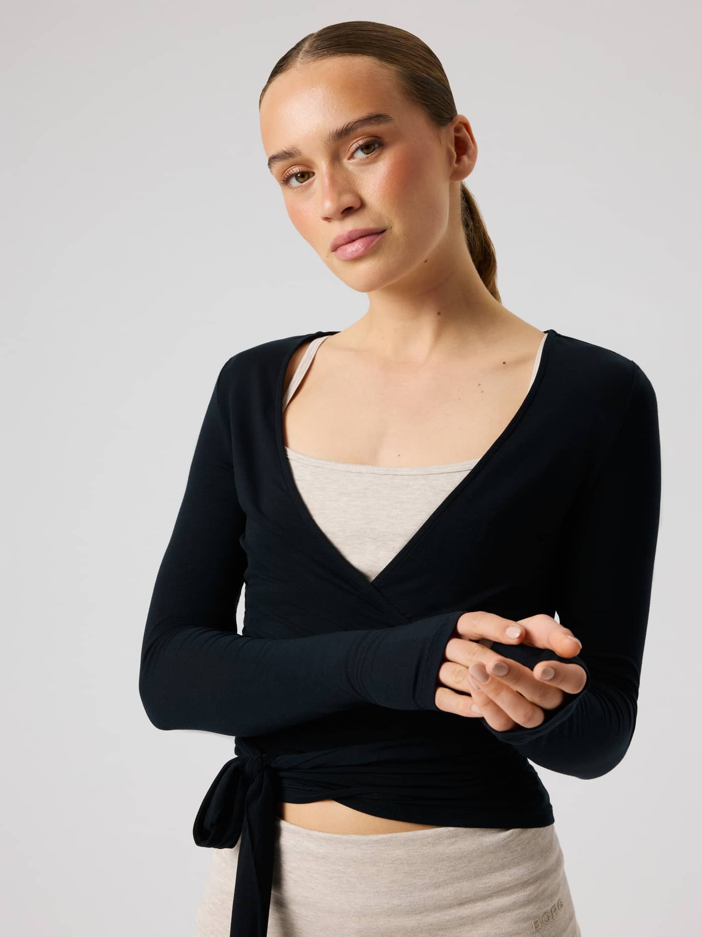 Front view of a model wearing the Studio Wrapped Top in Black Beauty (Black), a slim training top with a wrap-around waist. - Image 6