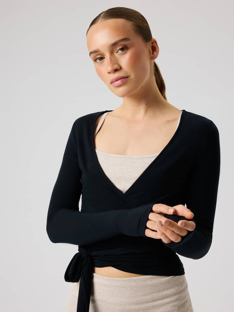 Front view of a model wearing the Studio Wrapped Top in Black Beauty (Black), a slim training top with a wrap-around waist.