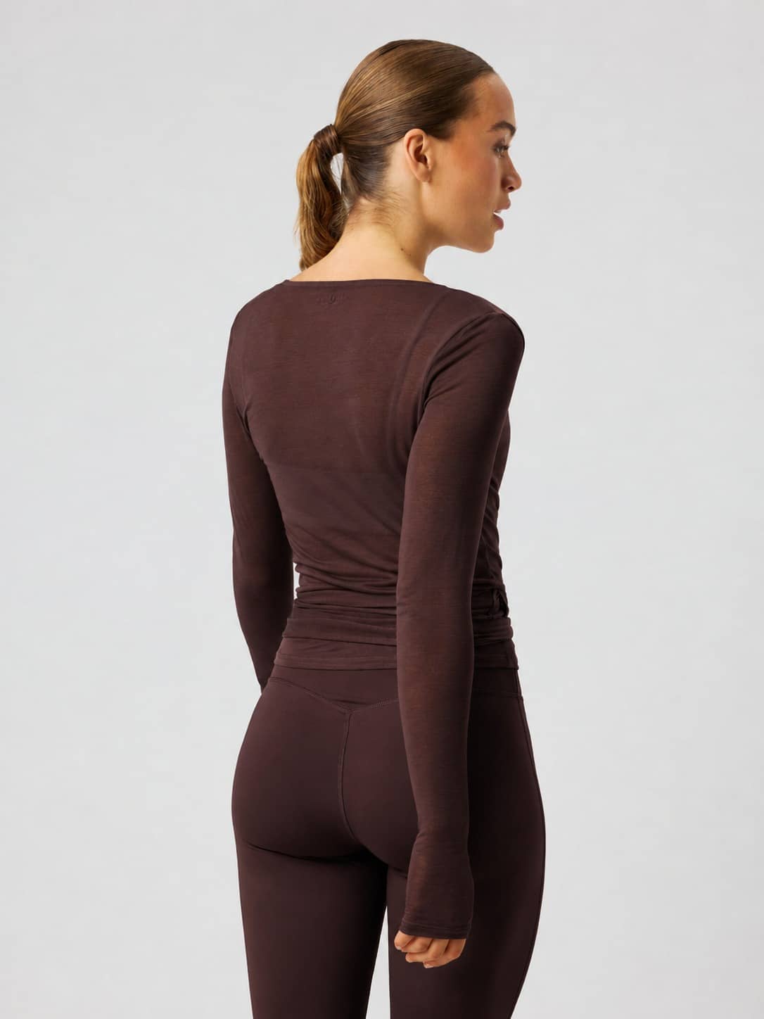 Back view of the Studio Wrapped Top in Coffee Bean (Brown), featuring a slim fit and long sleeves for studio training. - Image 3