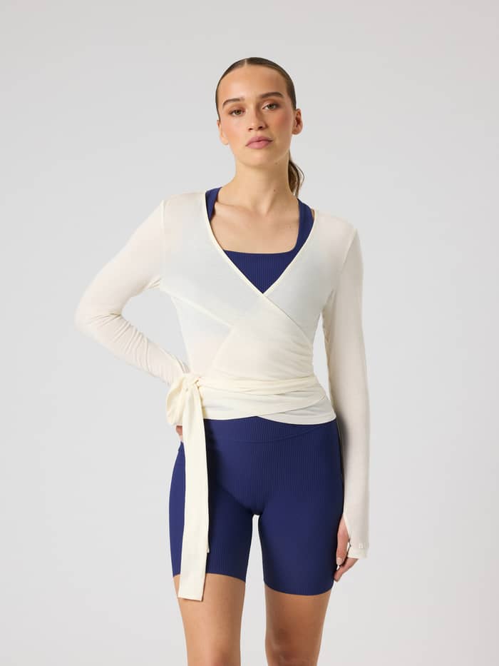Vorderansicht des Studio Wrapped Top in Tofu (Weiß) mit Wickel-Taille und weißem Logo für das Training.