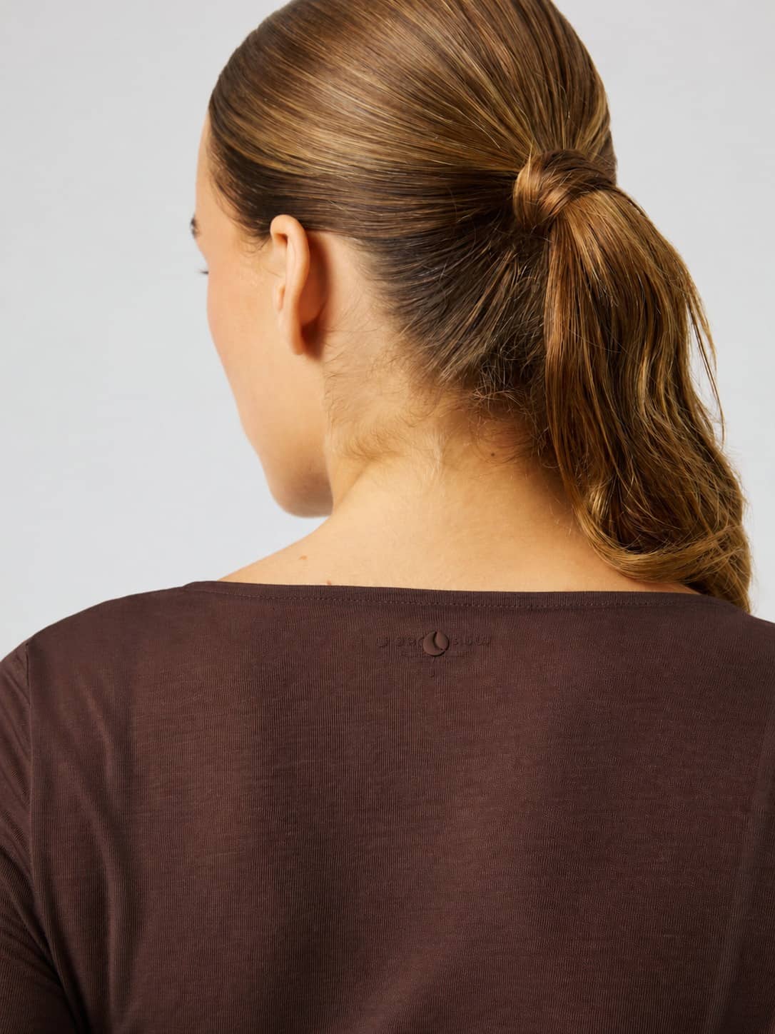 Back view of the Studio Wrapped Top in Coffee Bean (Brown) featuring a tonal logo at the neck for studio training. - Image 5