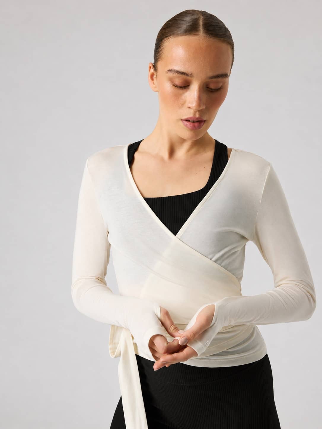 Front view of a model wearing the Studio Wrapped Top in Tofu (White) training top with a wrap waist. - Image 4
