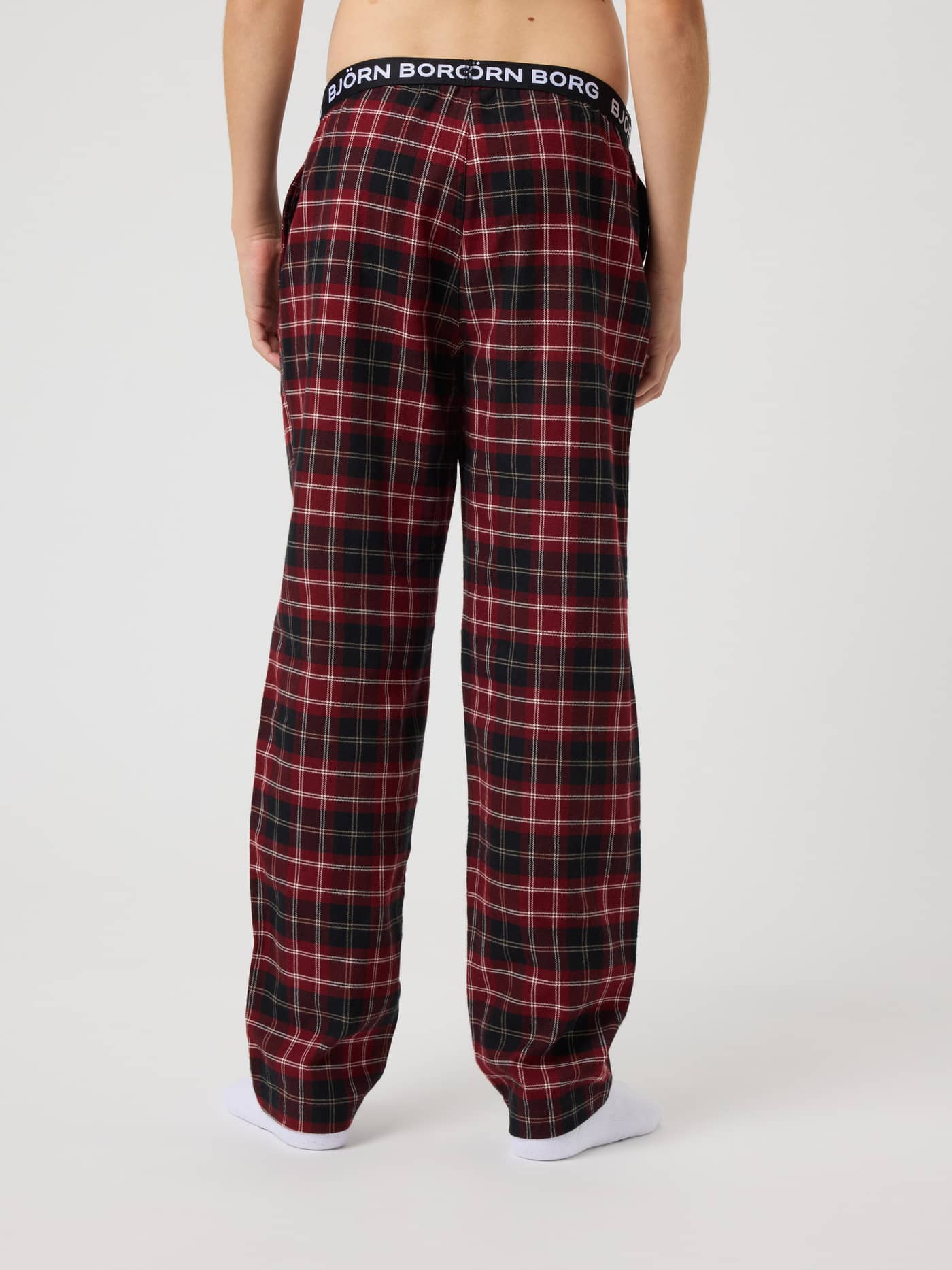Back view of kids in Core Flannel Pyjama Pants in red and black Forest Tartan with a white logo on the black waistband. - Image 3