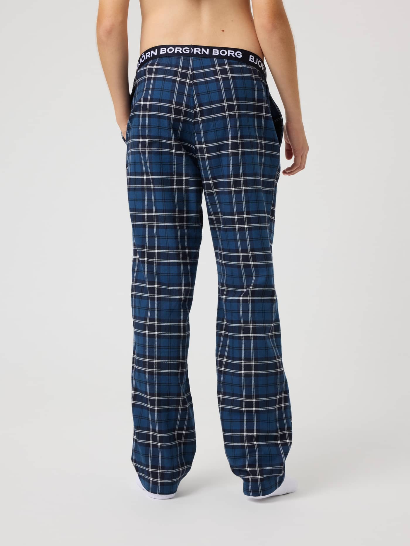 Back view of the kids Core Flannel Pyjama Pants in Forest Tartan 4 (Green) with a tartan pattern and black logo waistband. - Image 3