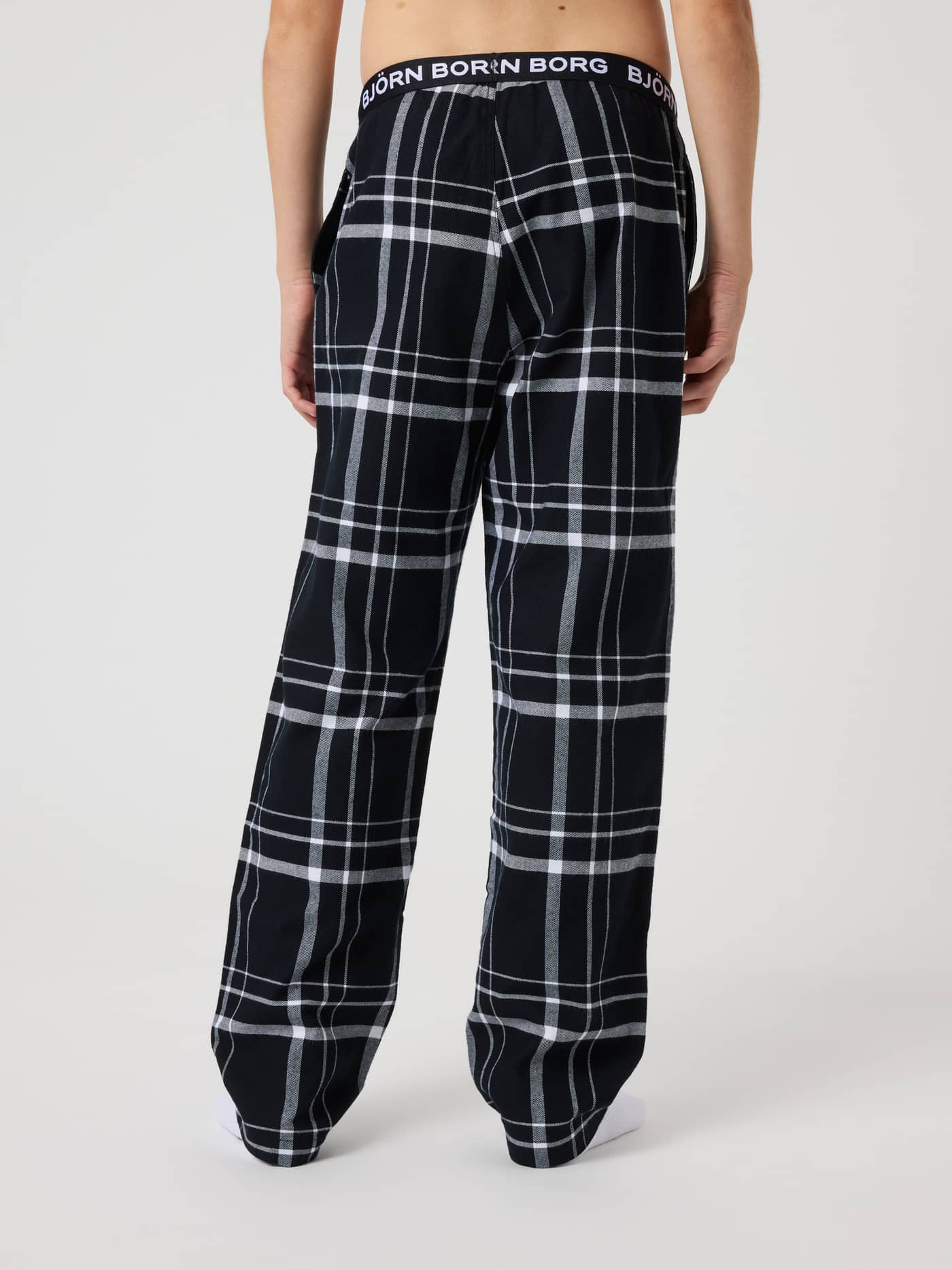 Back view of kids wearing Björn Borg Core Flannel Pyjama Pants in a black, white and grey checked pattern with a white logo. - Image 3