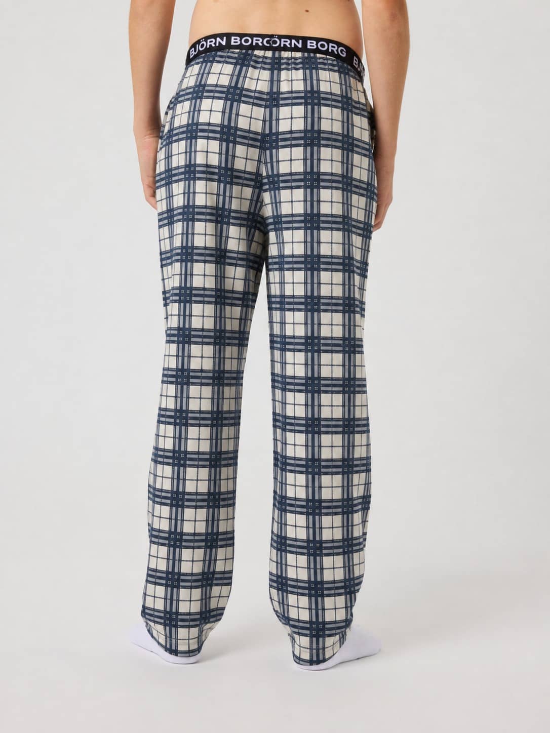 Back view of kids wearing Core Flannel Pyjama Pants in a blue, white and black tartan check with a white logo waistband. - Image 3