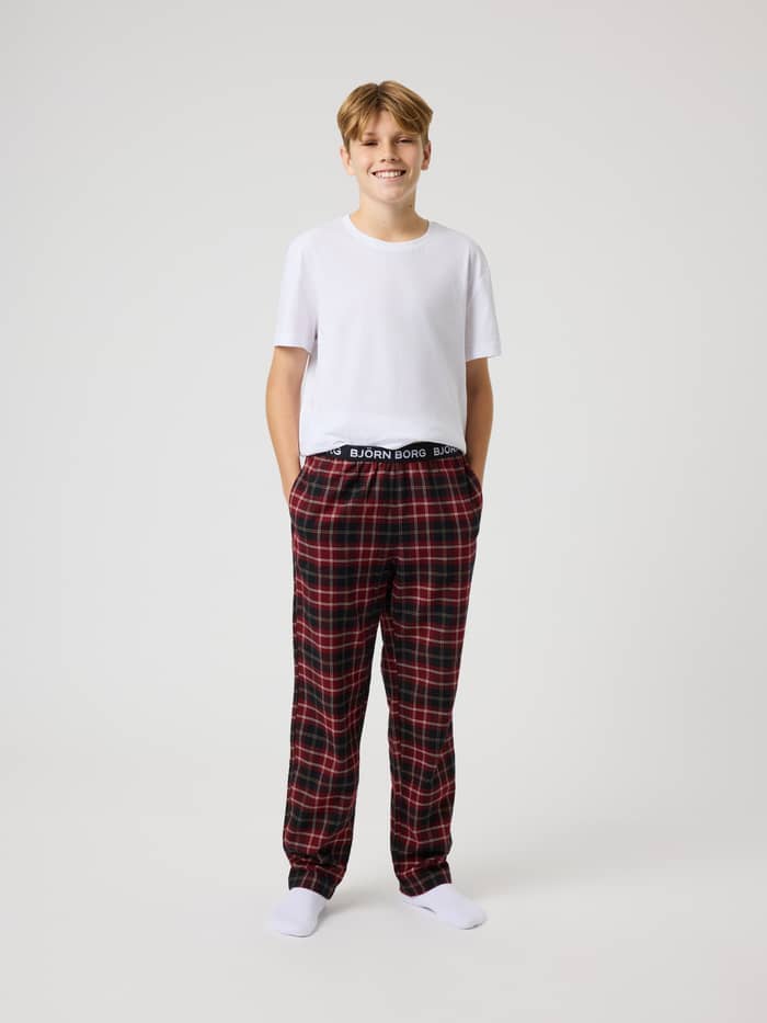 Full-body front view of kids wearing Core Flannel Pyjama Pants in Forest Tartan 11 (Black, Red) with a tartan pattern.