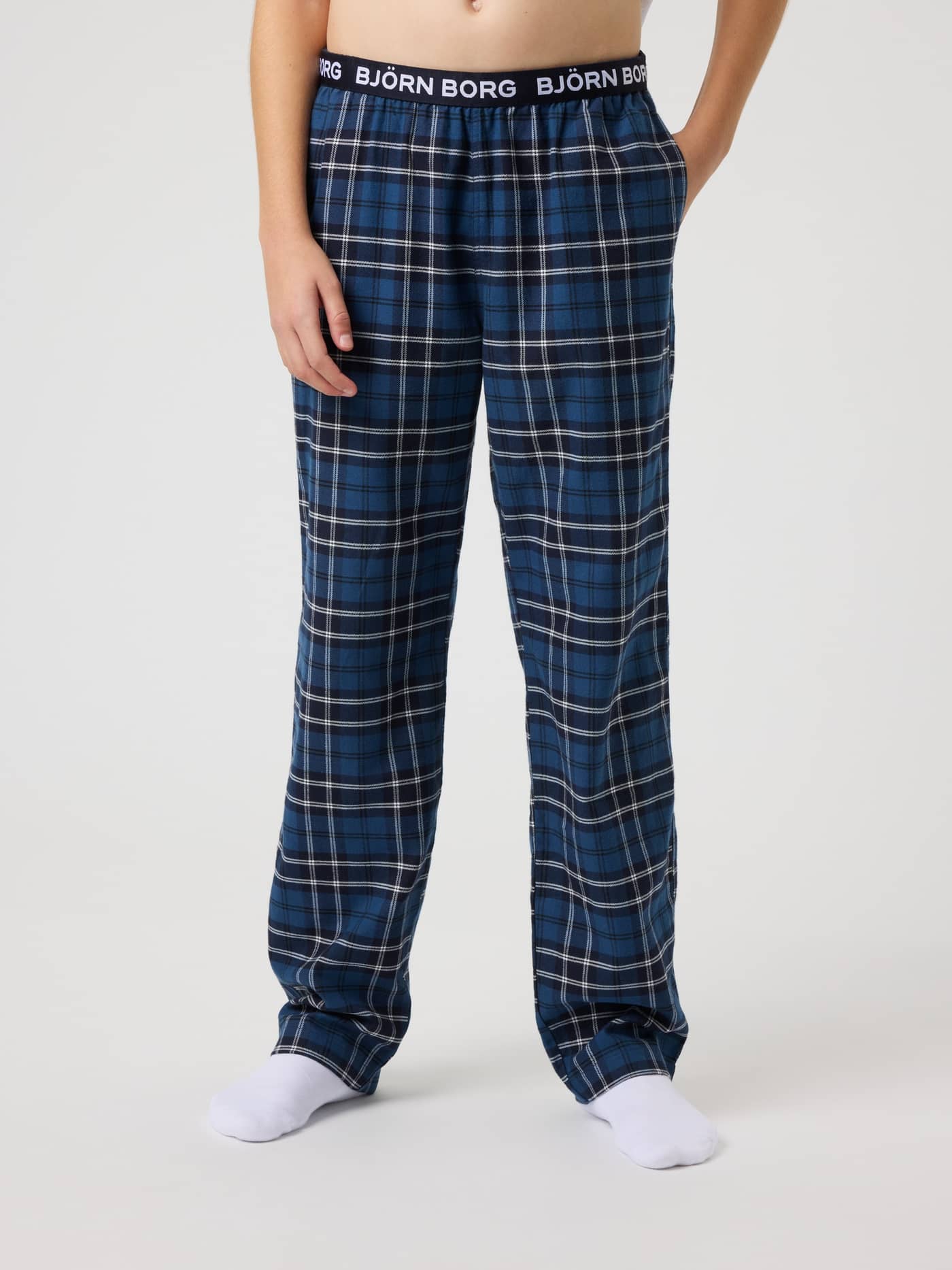 Front view of kids Core Flannel Pyjama Pants in a Forest Tartan 4 (Green) check with a white logo on a black waistband. - Image 2