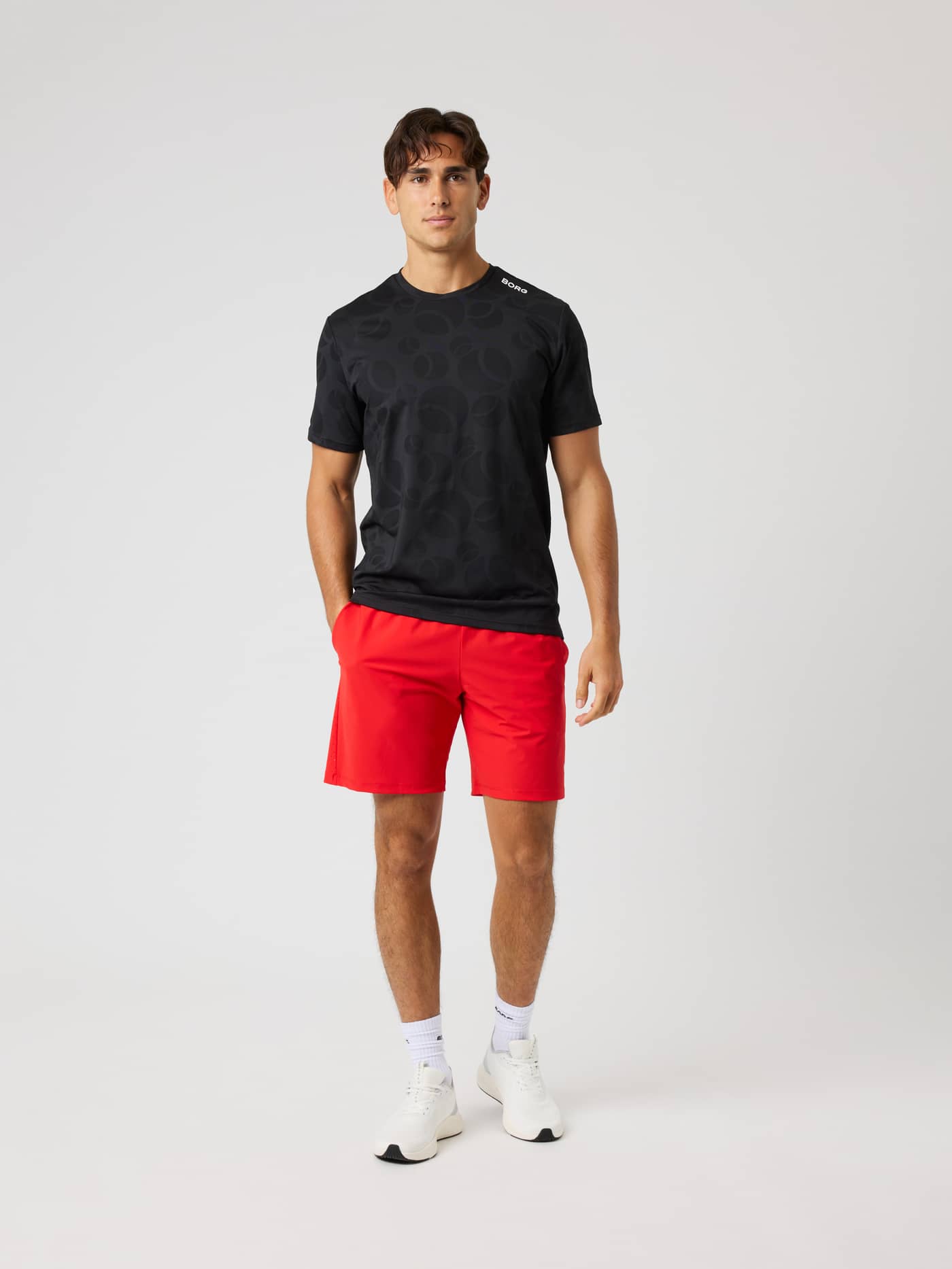 Full-body view of a man in the Ace Performance T-Shirt in Black Beauty (Black) with a tennis ball pattern and white logo. - Image 4