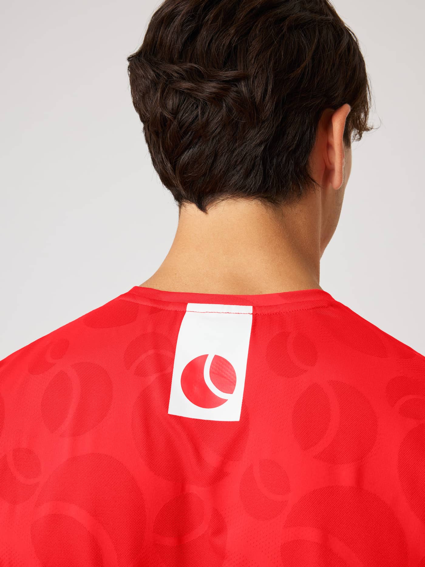 Back neck view of the Ace Performance T-Shirt in Flame Scarlet (Red) with a tennis ball jacquard pattern and red logo. - Image 5