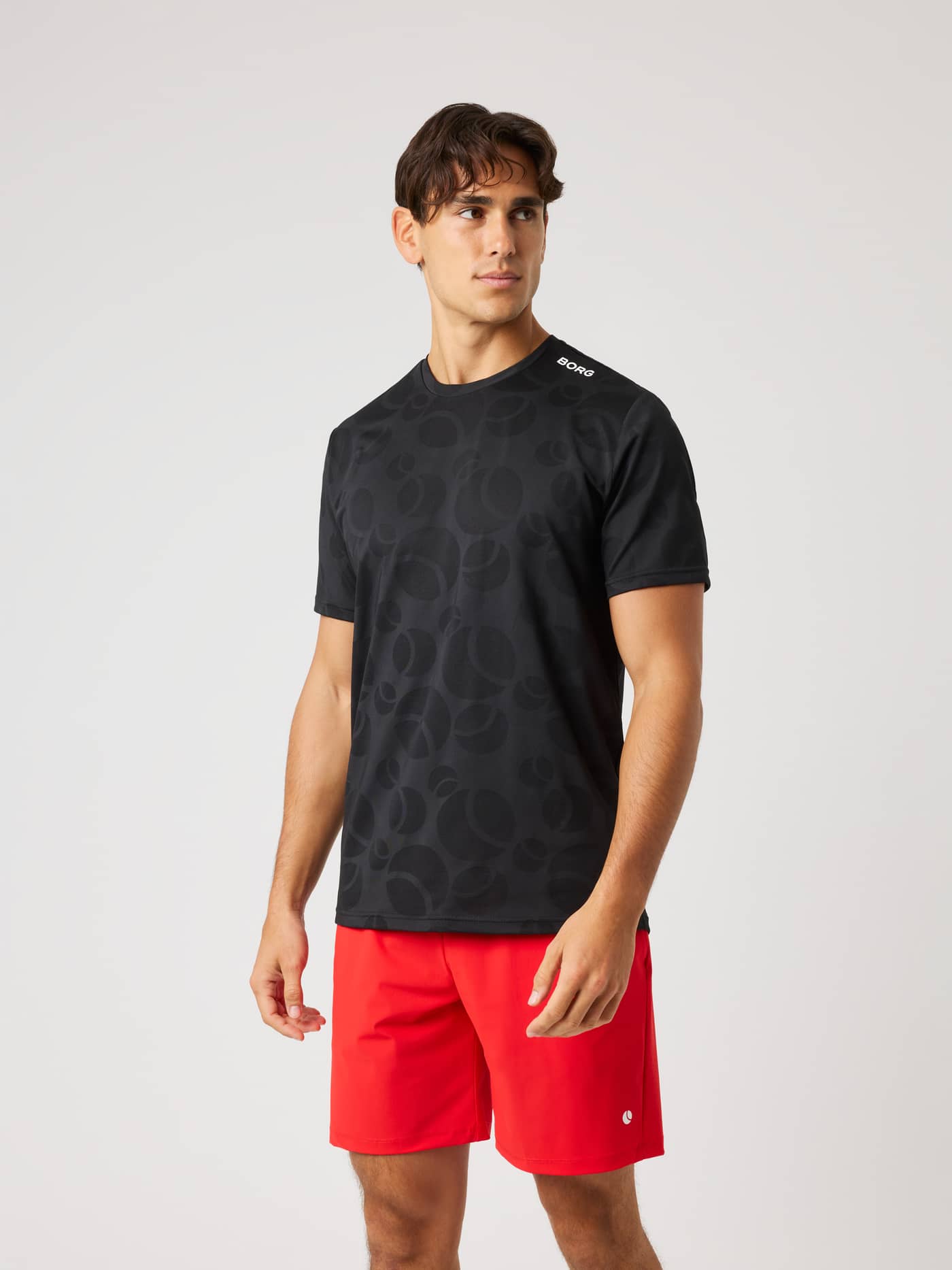 Front view of a man wearing the Ace Performance T-Shirt in Black Beauty (Black) with a tennis ball jacquard and white logo. - Image 2