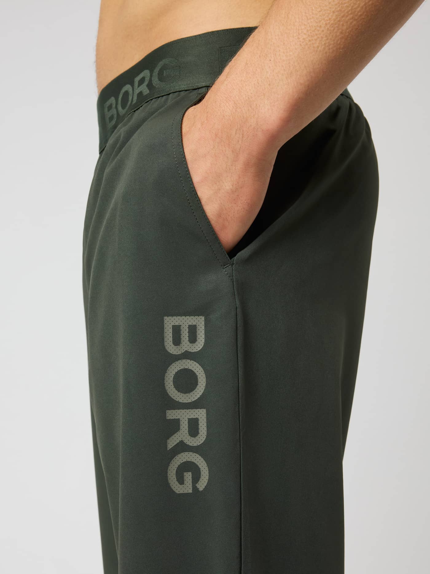 Side view of Borg Training Pants in Rosin (Green) with a perforated grey logo and branded waistband for training and tennis. - Image 4