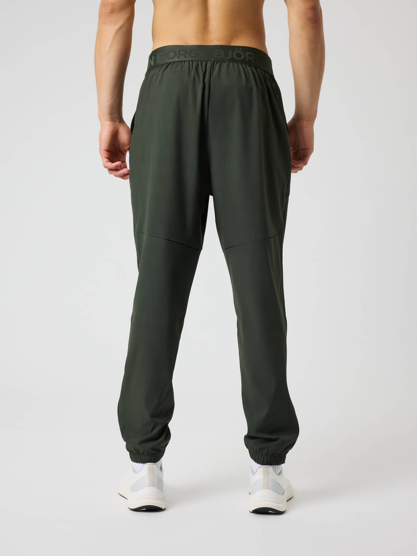 Back view of a man wearing Borg Training Pants in Rosin (Green), featuring a branded waistband for functional training. - Image 2