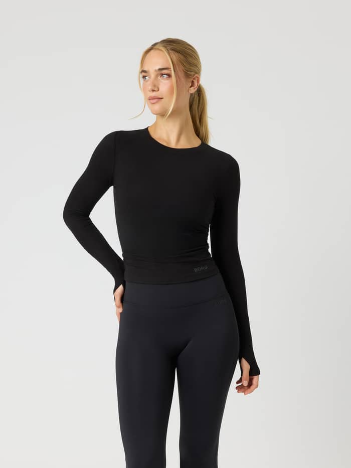 Voorzijde van de Studio Ribbed Cropped Long Sleeve in Black Beauty (zwart) met een ronde hals en mouwen met duimgaten.