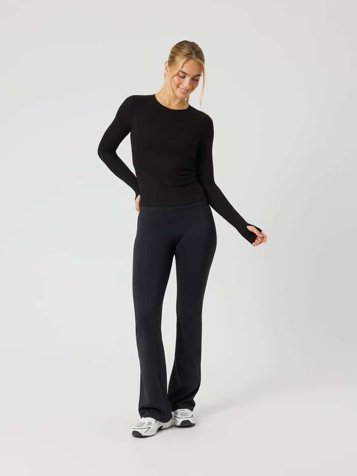 Voorzijde van de Studio Ribbed Cropped Long Sleeve in Black Beauty (zwart) met mouwen met duimgaten.