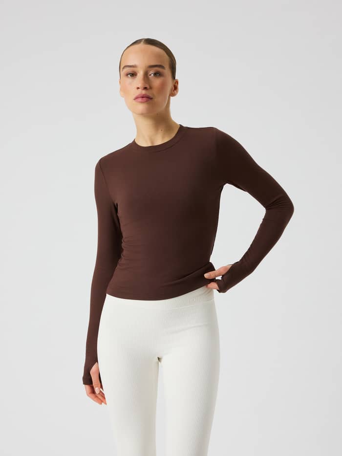 Front view of the Studio Ribbed Cropped Long Sleeve in Coffee Bean (Brown) with ribbed fabric and a tonal logo for training.