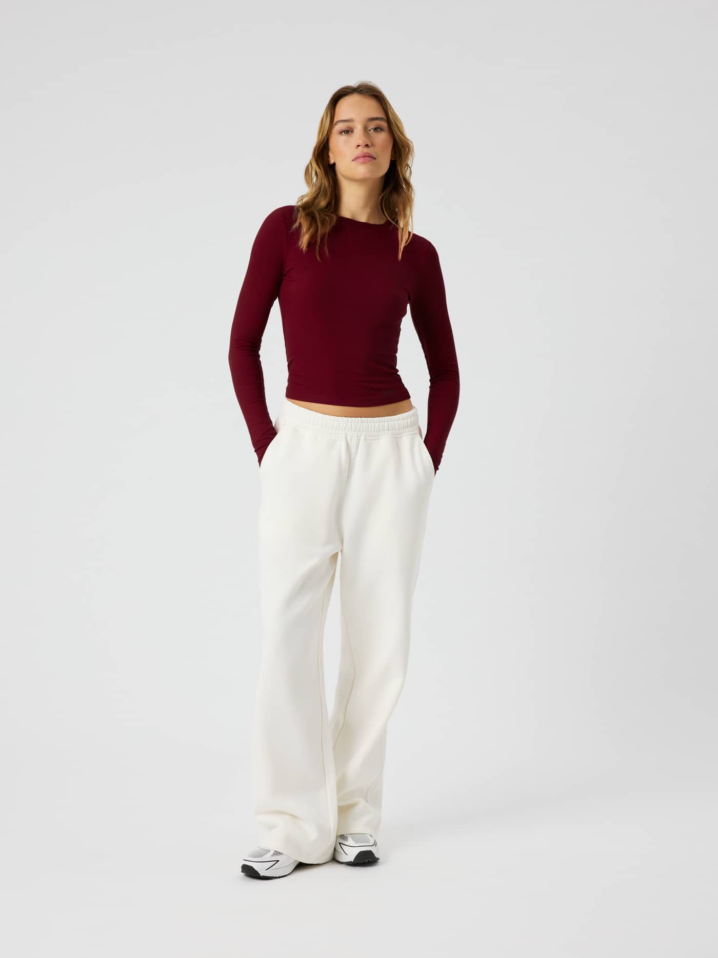STUDIO RIBBED CROPPED LONG SLEEVE i Cabernet (Röd) sedd framifrån tillsammans med vita mjukisbyxor. - Image 3