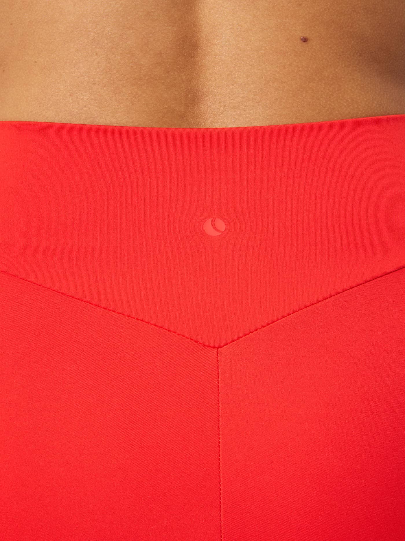 Close-up of the Studio Soft Tights in Flame Scarlet (Red) featuring a tonal tennis ball logo for training comfort. - Image 5