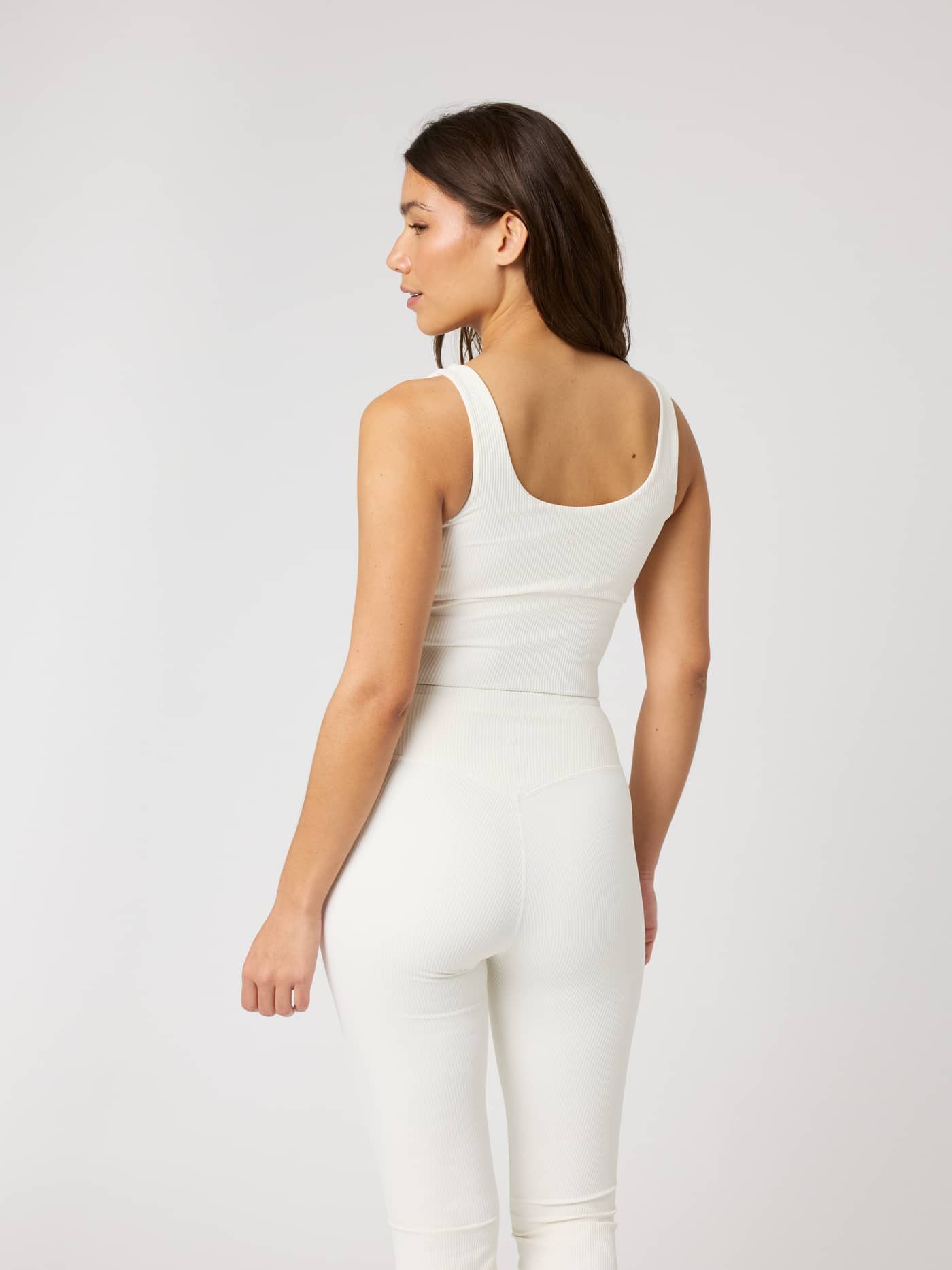 Back view of a woman wearing the Studio Ribbed V-Neck Top in Tofu (White) with a ribbed texture for training. - Image 2