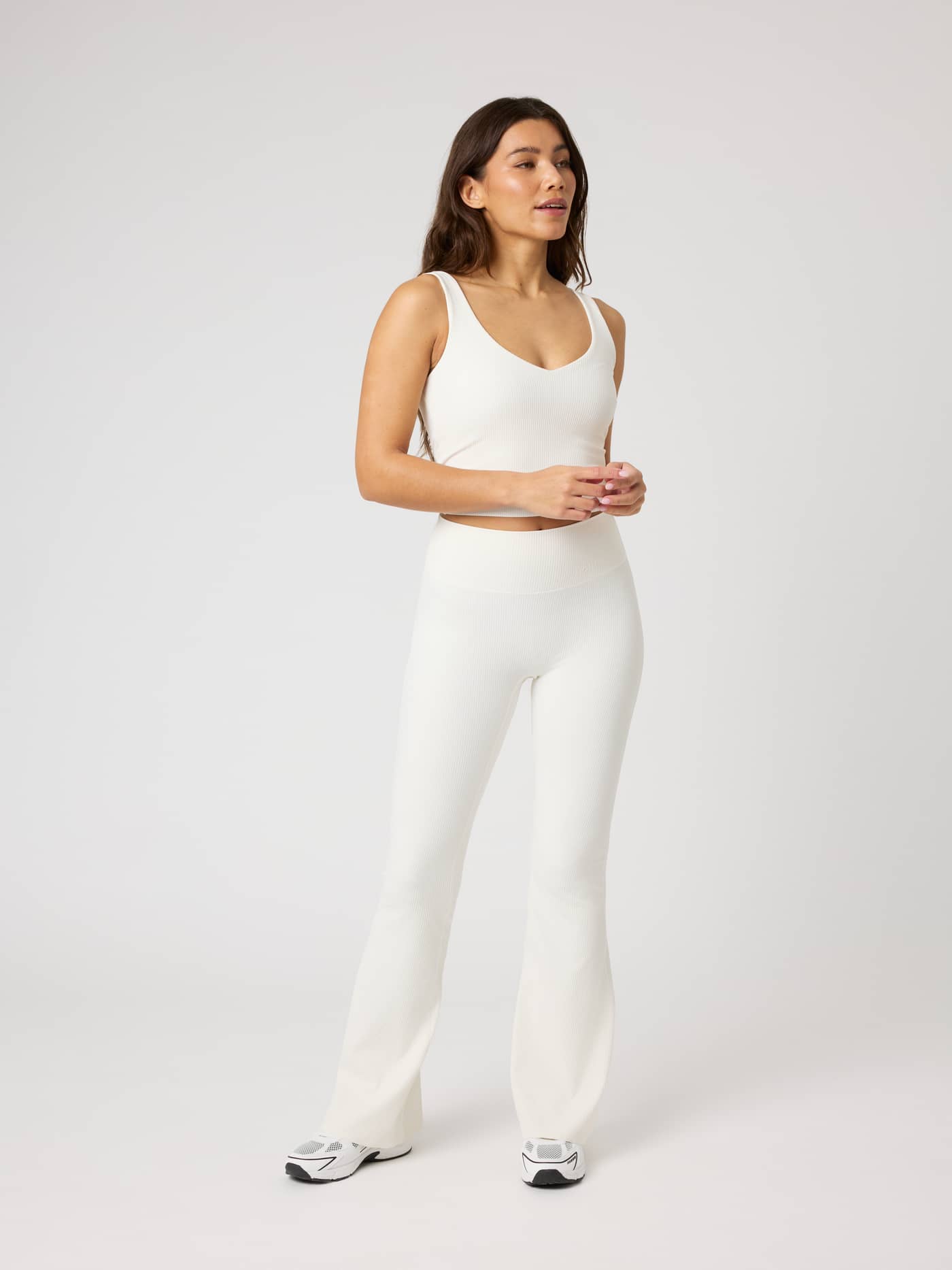 Full-body view of a model in the Studio Ribbed V-Neck Top in Tofu (White), a slim-fit ribbed training tank. - Image 3